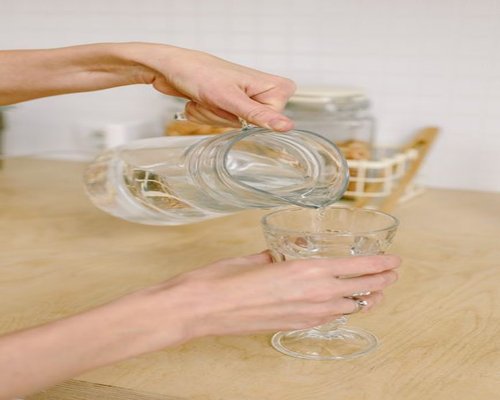 A clear glass being filled with fresh water for essential daily hydration goals
